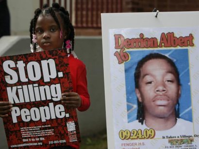 Nadashia Thomas, 6, a cousin of Derrion Albert, holds a sign that reads, "Stop killing people" beside a poster of him at Fenger High School. 