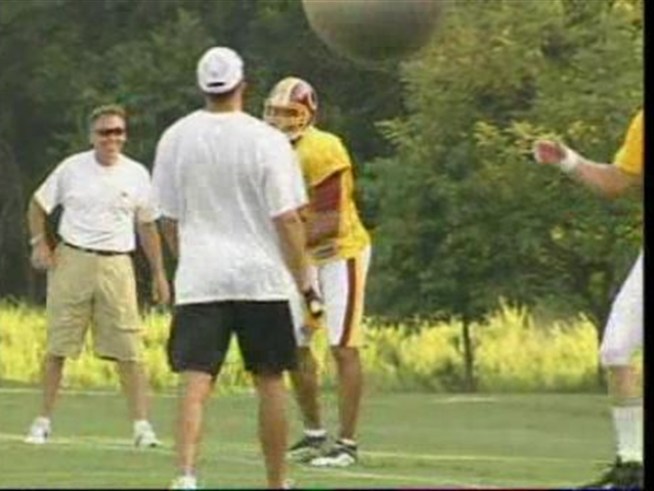 Jason Campbell gets tripped up by some large balls during a training camp QB drill.