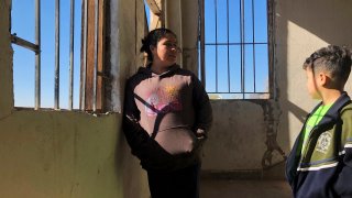 Enma Floriana chats with her 13-year-old son in the stairway of a migrant shelter in Mexicali, Mexico.