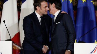 Emmanuel Macron, left, puts his arm around the shoulder of Italian Premier Giuseppe Conte and gives him a kiss on both cheeks.