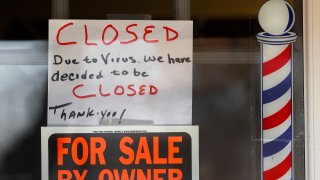 In this April 2, 2020, file photo, "For Sale By Owner" and "Closed Due to Virus" signs are displayed in the window of Images On Mack in Grosse Pointe Woods, Mich.