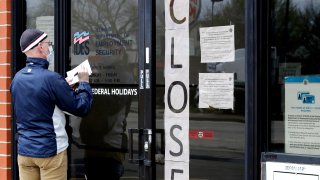 In this April 30, 2020, file photo, a man writes information in front of Illinois Department of Employment Security in Chicago, Illinois.