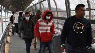 In this Saturday, March 21, 2020 file photo, Central American migrants seeking asylum, some wearing protective face masks, return to Mexico via the international bridge at the U.S-Mexico border that joins Ciudad Juarez and El Paso