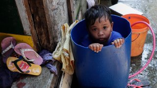 A boy takes a bath inside a plastic container at a coastal village in Cavite province, south of Manila, Philippines, during a continuing enhanced community quarantine to prevent the spread of the new coronavirus, Thursday, May 7, 2020.