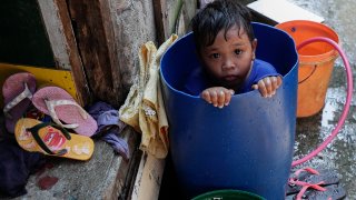 A boy takes a bath inside a plastic container at a coastal village in Cavite province, south of Manila, Philippines, during a continuing enhanced community quarantine to prevent the spread of the new coronavirus, Thursday, May 7, 2020.