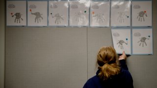 FILE - In this May 12, 2020, file photo, a teacher removes students’ artwork from a bulletin board as she packs the art in her kindergarten classroom at an elementary school in Olathe, Kan.