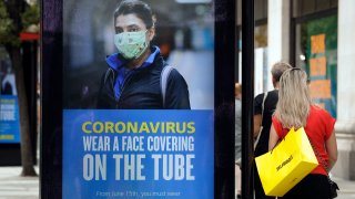 People walk with bags after shopping at the Selfridges department store in London, Monday, June 15, 2020. Researchers in England say they have the first evidence that a drug can improve COVID-19 survival.
