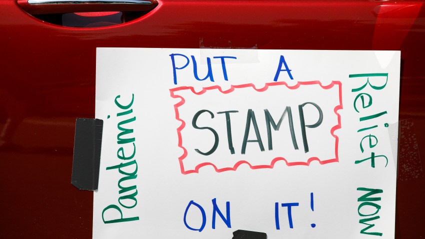 Part of a car caravan of postal employees has a sign on it asking Congress to approve emergency funding for the Postal Service, Tuesday, June 23, 2020, on Capitol Hill in Washington.