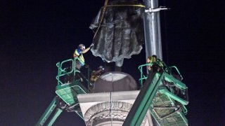 Crews use cranes to affix straps to a statue of former vice president and slavery advocate John C. Calhoun as part of the process of removing it from a 100-foot-tall monument in downtown Charleston, S.C., on Wednesday, June 24, 2020.