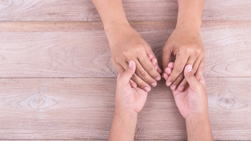 Help and support Concept : Woman holds her young kids hands on brown wooden table. Free space for text or design