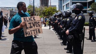 A man holds a Black Lives Matter sign in front of the San Diego Police in downtown San Diego, California on May 31, 2020 as they protest the death of George Floyd.