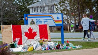 A woman comforts her daughter after they placed flowers at an impromptu memorial in front of the RCMP detachment on April 20, 2020, in Enfield, Nova Scotia, Canada.