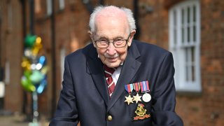 In this April 16, 2020, file photo, British World War II veteran Captain Tom Moore, 99, poses doing a lap of his garden in the village of Marston Moretaine, 50 miles north of London.