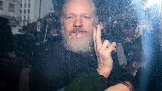 In this file photo, Julian Assange gestures to the media from a police vehicle on his arrival at Westminster Magistrates court on April 11, 2019 in London, England.
