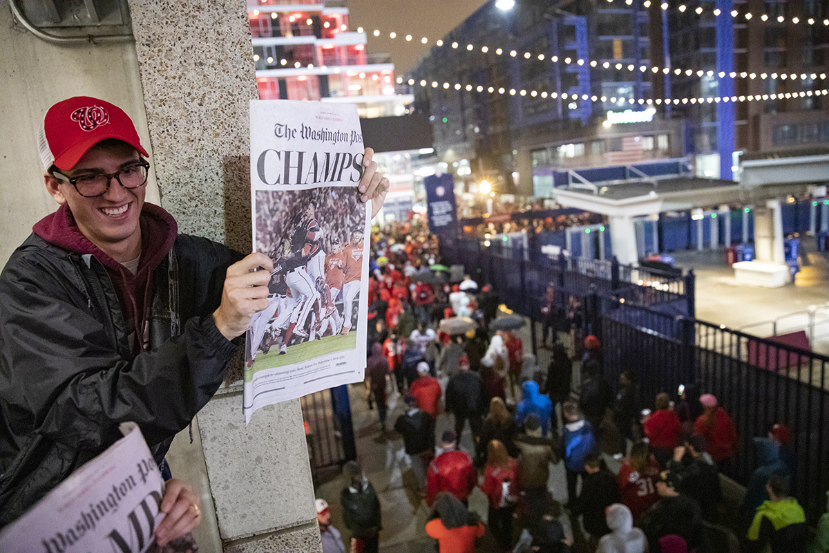 James Benner, a Georgetown student from Boston, holds up the front page of the Washington Post announcing the Washington Nationals' victory. (Photo by Samuel Corum/Getty Images)