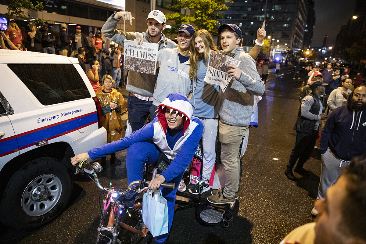 Nationals fans pose for a photograph with a pedicab drive dressed in a Baby Shark costume and with the front page of the Washington Post outside of Nationals Park as they celebrate the Nationals' World Series victory. (Photo by Samuel Corum/Getty Images)