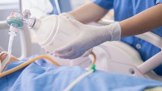 doctor holding oxygen ambu bag over patient given oxygen to patient by intubation tube