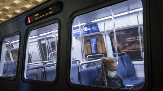 A commuter wears a protective face mask while riding on a subway train in Washington, D.C., U.S., on Monday, March 16, 2020.