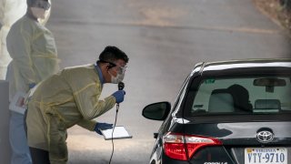 James Meenan, director of Virginia Hospital Center outpatient lab, gives directions to a patient at a drive-through coronavirus testing site on March 18, 2020 in Arlington, Virginia.