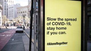 A MUNI bus stop sign displays an advertisement placed by the Center for Disease Control (CDC) reading “Slow the spread of COVID-19, stay home if you can” in San Francisco.