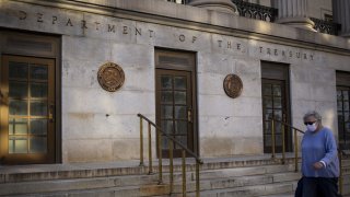 A pedestrian wearing a protective mask passes the U.S. Treasury building