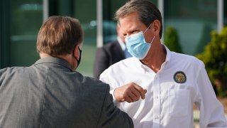 Brian Kemp, governor of Georgia, wears a protective mask while bumping elbows with an attendee during a 'Wear A Mask' tour stop in Dalton, Georgia, on July 2, 2020.