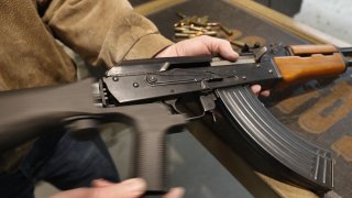 A bump stock is installed on an AK-47 and its movement is demonstrated at a gun range.