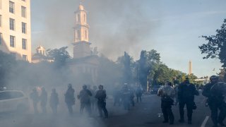 Tear gas floats in the air as a line of police move demonstrators away from St. John's Church across Lafayette Park from the White House, as they gather to protest the death of George Floyd, Monday, June 1, 2020, in Washington.