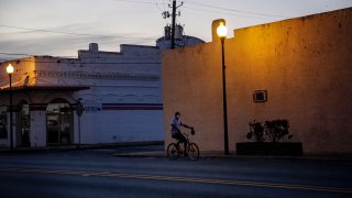 In this April 17, 2020, file photo, a man rides a bicycle down an empty street in Dawson, Georgia.