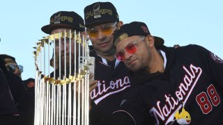 Washington Nationals relief pitcher Sean Doolittle, starting pitcher Anibal Sanchez and center fielder Gerardo Parra take photos in of the commissioner's trophy while on stage at a rally Nov. 2, 2019, in Washington, D.C.