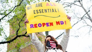 Natalie Brown, of Mt. Airy, Md., holds a sign in front of St. Anne’s Episcopal Church, during a demonstration to demand that Gov. Larry Hogan (R) lift restrictions that have closed certain businesses in Maryland since the coronavirus outbreak on Church Circle in Annapolis, Md., on Saturday, April 18, 2020. The event titled Operation Gridlock Annapolis was hosted by the Patriot Picket and Reopen Maryland. (Photo By Tom Williams/CQ-Roll Call, Inc via Getty Images)