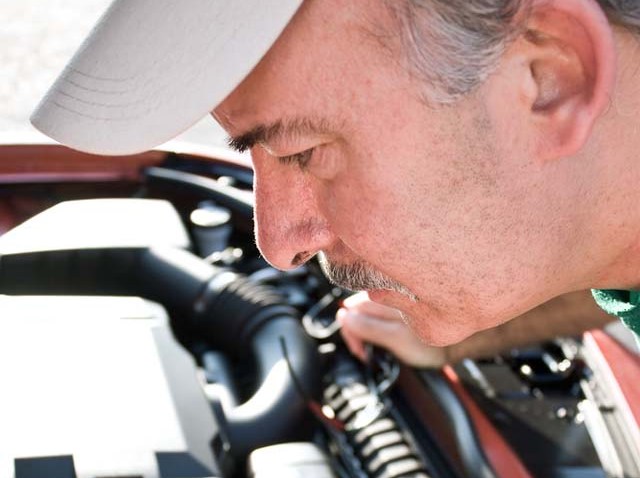 man inspecting car engine