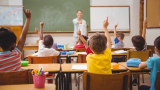 Pupils raising their hands during class in elementary school