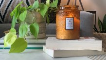 A candle sits atop books on a desk.