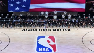 Members of the New Orleans Pelicans and Utah Jazz kneel together around the Black Lives Matter logo on the court during the national anthem before the start of an NBA basketball game Thursday, July 30, 2020, in Lake Buena Vista, Fla.