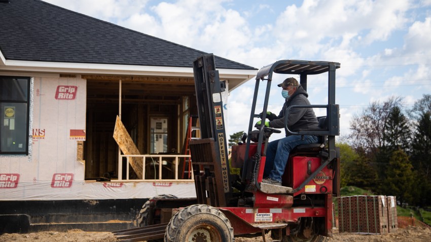 A construction worker wearing a protective mask moves bricks to the back of a house as they resume construction on a home in Bloomfield Hills, Michigan, U.S., on Thursday, May 7, 2020. Michigan Governor Gretchen Whitmer is giving the state's construction companies the green light to resume work on Thursday, as well as Detroits three carmakers and other manufacturers approval to open up factories starting May 11.