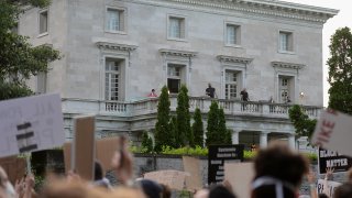 Security personnel stand on the balcony of the home of Mark and Patricia McCloskey as protesters demonstrate against racism and police brutality outside their neighborhood on July 3, 2020, in St Louis, Missouri.