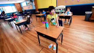 In this July 9, 2020, file photo, children in a pre-school class wear masks and sit at desks spaced apart as per coronavirus guidelines during summer school sessions in Monterey Park, California.