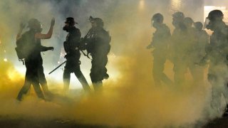 In this July 4, 2020, file photo, police confront demonstrators as Black Lives Matter supporters demonstrate at Portland's Justice Center in Portland, Oregon, for the 38th day in a row. A riot was declared after midnight.