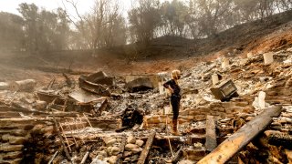 Pam, who declined to give a last name, examines the remains of her partner's Vacaville, Calif., home