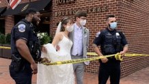 A bride and groom and two police officers stand behind yellow tape at the Four Seasons Hotel after its evacuation.