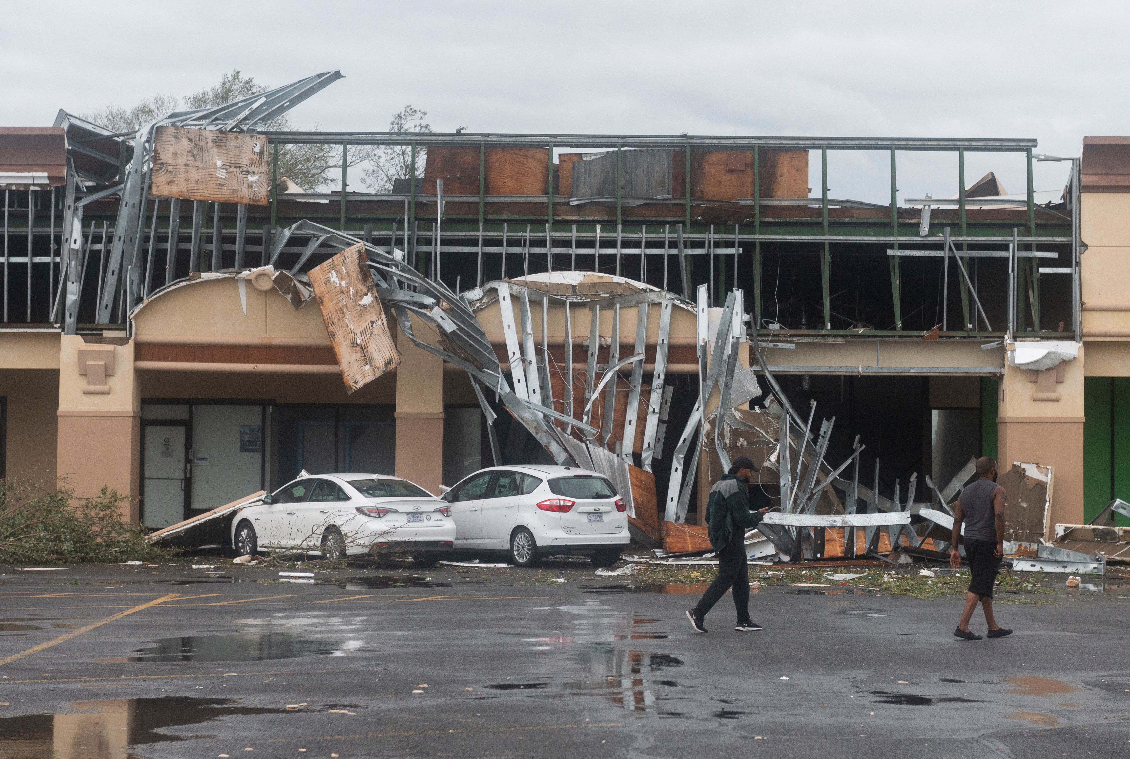 People walk past a destroyed building after the passing of Hurricane Laura in Lake Charles, Louisiana, Aug. 27, 2020. Hurricane Laura slammed into Louisiana Thursday, with the monster category 4 storm prompting warnings of &#8220;unsurvivable&#8221; ocean surges and evacuation orders for hundreds of thousands of Gulf Coast residents.