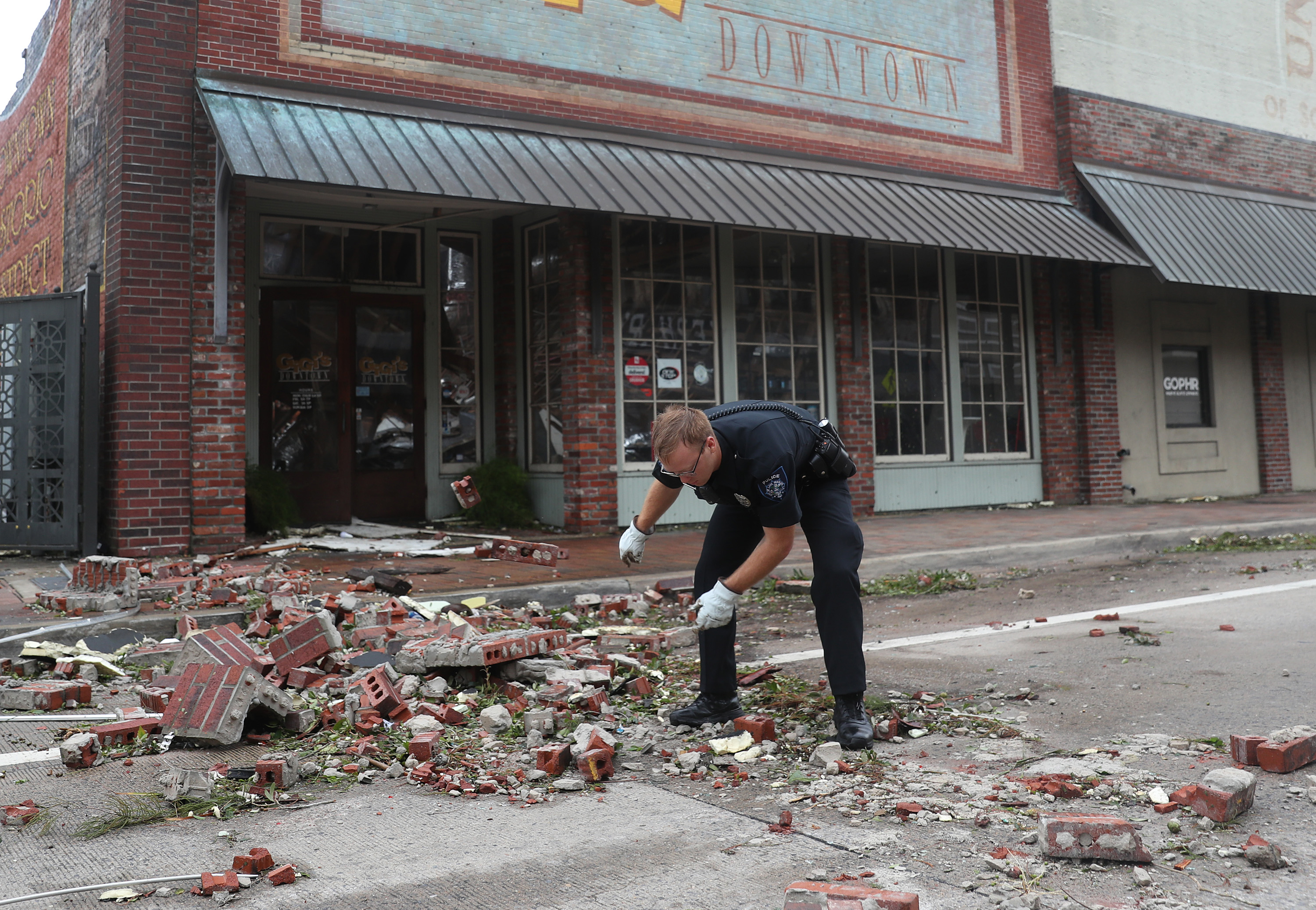 A Lake Charles police officer helps clear the streets of rubble in the downtown area after Hurricane Laura passed through on Aug. 27, 2020 in Lake Charles, Louisiana.