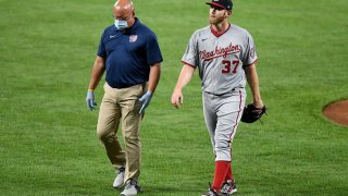 Stephen Strasburg walks off the field with trainer Paul Lessard after coming out of the game in the first inning against the Baltimore Orioles at Oriole Park at Camden Yards.