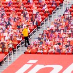A lone stadium usher stands among rows of plastic fan cut-outs placed in empty seats