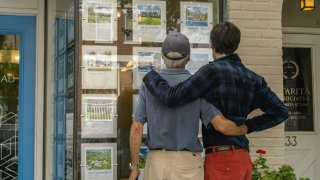 Pedestrians view homes for sale displayed in the window of a real estate office in Southampton, New York