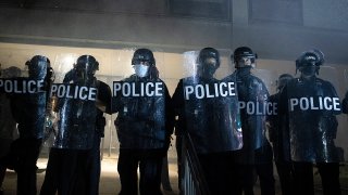 In this Oct. 28, 2020, file photo, police officers stand guard outside the 4th District Police Station during the second night of protest against the death of Karon Hylton in Washington, D.C.