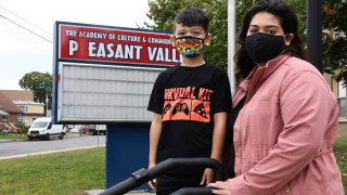 Kristina Negron poses for a photograph with her son, Mason Negron, 6, at his Pleasant Valley Elementary school, Sept. 29, 2020, in Schenectady, N.Y. Negron was laid off from her job as an aide for a special education class at Schenectady High School due to budget cuts.