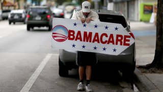 Pedro Rojas holds a sign directing people to an insurance company where they can sign up for the Affordable Care Act, also known as Obamacare