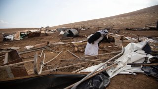 A Palestinian sifts through destroyed tents